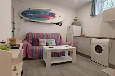 a living room with a couch and a surfboard on the wall at Apartamento a pie de playa. in Chiclana de la Frontera