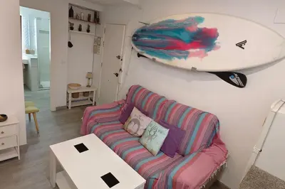 a living room with a couch and a surfboard on the wall at Apartamento a pie de playa. in Chiclana de la Frontera