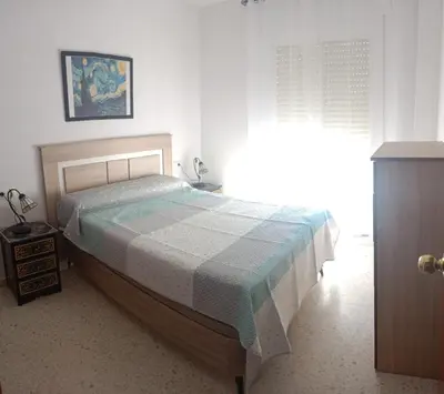 a bedroom with a bed with a blue and white blanket at Apartamento El Niño de Oro in Sanlúcar de Barrameda