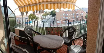 a balcony with a table and chairs and a view of a city at Apartamento El Niño de Oro in Sanlúcar de Barrameda