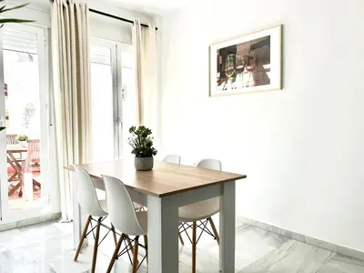 a dining room with a wooden table and white chairs at Alojanómadas Jerez Centro in Jerez de la Frontera