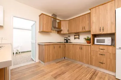a kitchen with wooden cabinets and a microwave at El Paseo del Faro in Chipiona