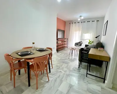 a dining room and living room with a table and chairs at Las Antillas by RentCadiz in El Puerto de Santa María