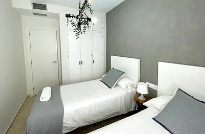 a bedroom with two beds and a chandelier at Las Antillas by RentCadiz in El Puerto de Santa María
