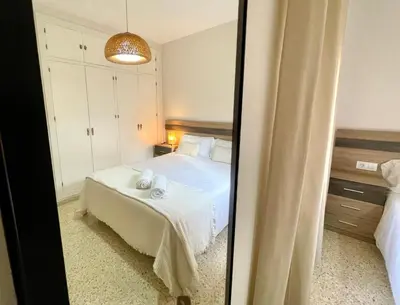 a bedroom with a white bed and a mirror at Las Antillas by RentCadiz in El Puerto de Santa María