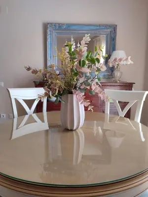a vase with flowers on a glass table with two chairs at Mina42 by 7Escalones in Rota