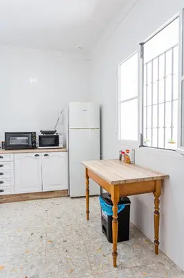 a kitchen with a wooden table and a refrigerator at Carril San Diego, junto a la Plaza Cabildo in Sanlúcar de Barrameda