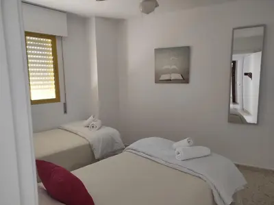 two beds in a room with white walls and a window at Valdelagrana Marinero in El Puerto de Santa María