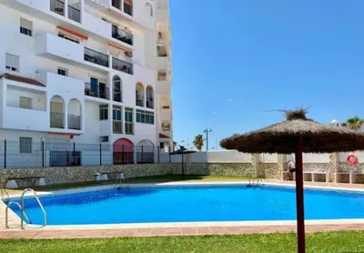 a swimming pool with an umbrella next to a building at Valdelagrana Marinero in El Puerto de Santa María