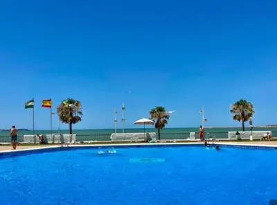 a large blue swimming pool next to the beach at Valdelagrana Marinero in El Puerto de Santa María