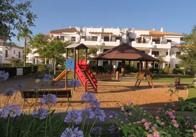 a playground in a park with purple flowers at Segunda planta con terraza y solarium in Chiclana de la Frontera