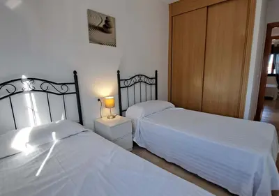 a bedroom with two beds and a lamp on a night stand at Segunda planta con terraza y solarium in Chiclana de la Frontera