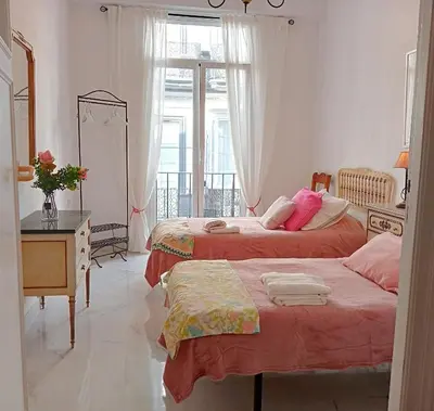 a bedroom with two beds and a desk and a window at Casa Palacio Madre de la Eucaristía in El Puerto de Santa María