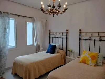 a bedroom with two beds and a chandelier at Casa Palacio Madre de la Eucaristía in El Puerto de Santa María