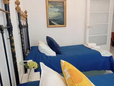 two beds in a room with blue sheets and pillows at Casa Palacio Madre de la Eucaristía in El Puerto de Santa María