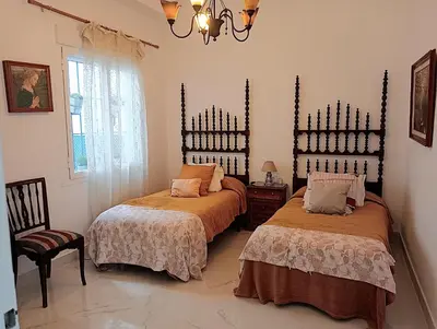 a bedroom with two beds and a chandelier at Casa Palacio Madre de la Eucaristía in El Puerto de Santa María
