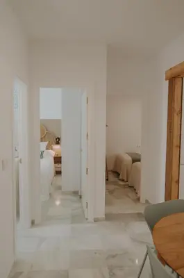 a room with white walls and a hallway with a table at Apartamento El Mazacote Sanlúcar de Barrameda in Sanlúcar de Barrameda