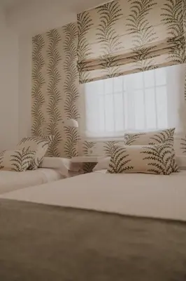 a white bedroom with two beds and a window at Apartamento El Mazacote Sanlúcar de Barrameda in Sanlúcar de Barrameda