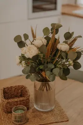 a vase with white roses and greenery on a table at Apartamento El Mazacote Sanlúcar de Barrameda in Sanlúcar de Barrameda