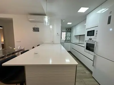 a kitchen with a bar with chairs and a counter top at Moderno Apartamento Primera Línea Playa de La Barrosa by ChiclanaDreams in Chiclana de la Frontera