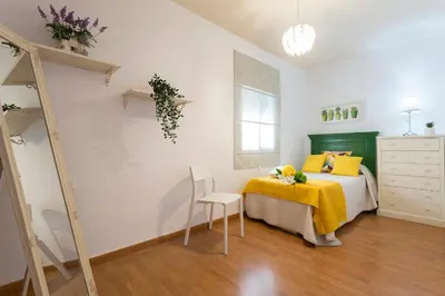 a bedroom with a bed with yellow pillows and a chair at Centrico Tranquilo 2 Rooms in Jerez de la Frontera