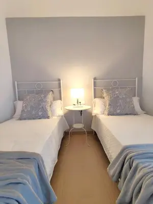 two beds in a room with a table between them at Oloroso Home CERCA CENTRO in Jerez de la Frontera