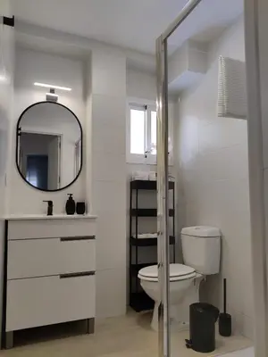 a white bathroom with a toilet and a mirror at Oloroso Home CERCA CENTRO in Jerez de la Frontera