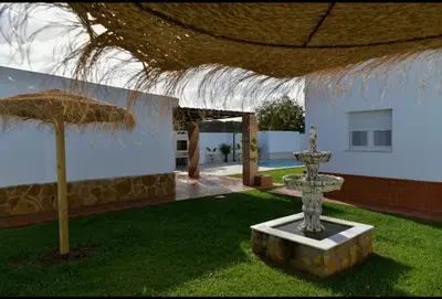 a fountain in front of a building with an umbrella at Villa Luna Novo Santi Petri in Chiclana de la Frontera