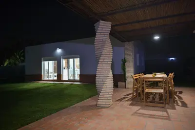 a table and chairs on a patio at night at Villa Luna Novo Santi Petri in Chiclana de la Frontera