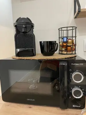 a black microwave on a shelf with a coffee maker at Apartamentos Corredera 3 in Arcos de la Frontera