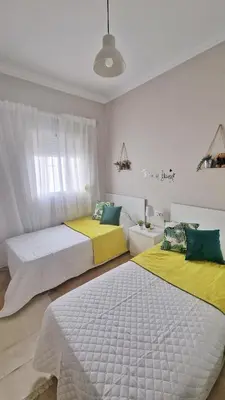 two beds in a room with yellow and green at Villas Luins in Chiclana de la Frontera