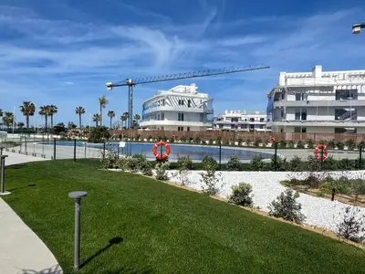 a park in front of a building with a crane at Costa Ballena - Dos dormitorios, Piscina y Jardín privado in Cádiz