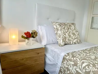 a bed with a pillow and a candle on a night stand at GATU Cream, terraza, parking, aire acc, piscina común 