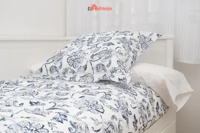 a bed with a blue and white blanket and a pillow at El Anfitrión - Carmen Viejo in Sanlúcar de Barrameda