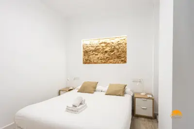 a bedroom with a white bed and a painting on the wall at Bajo el Falla by Cadiz Time in Cádiz