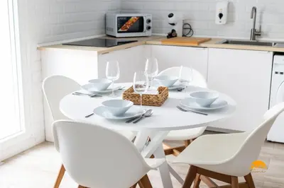 a white kitchen with a white table and chairs at Bajo el Falla by Cadiz Time in Cádiz