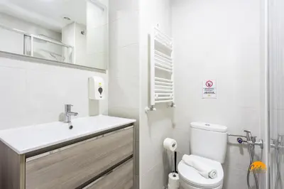 a white bathroom with a toilet and a sink at Bajo el Falla by Cadiz Time in Cádiz