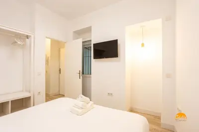 a white bedroom with a bed and a tv at Bajo el Falla by Cadiz Time in Cádiz