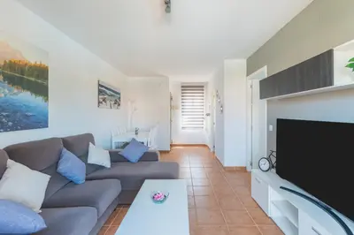 a living room with a couch and a flat screen tv at Urbanización Jardín del Golf 1 in Novo Sancti Petri