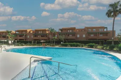 a large swimming pool in front of some apartments at Urbanización Jardín del Golf 1 in Novo Sancti Petri