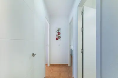a hallway with white walls and a glass door at Urbanización Jardín del Golf 1 in Novo Sancti Petri