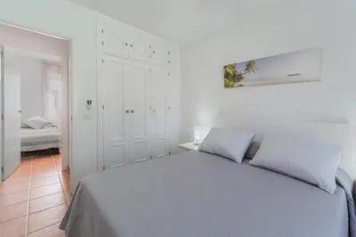 a white bedroom with a bed in a room at Urbanización Jardín del Golf 1 in Novo Sancti Petri