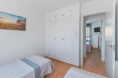 a white bedroom with a bed and a corridor at Urbanización Jardín del Golf 1 in Novo Sancti Petri