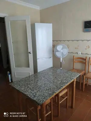 a kitchen with a table and a refrigerator at Piso primera línea de playa in Chipiona