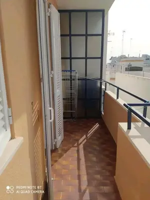a balcony with a door and a shopping cart at Piso primera línea de playa in Chipiona