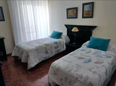 a bedroom with two beds and a window at Piso primera línea de playa in Chipiona