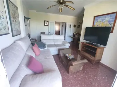 a living room with white couches and a flat screen tv at Piso primera línea de playa in Chipiona