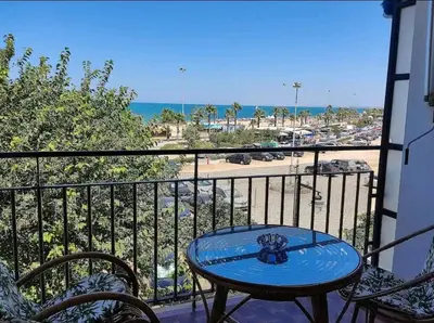 a table on a balcony with a view of the beach at Piso primera línea de playa in Chipiona