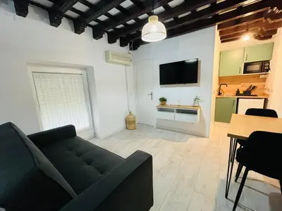 a living room with a black couch and a kitchen at Apartamento Jerez Centro San Miguel in Jerez de la Frontera