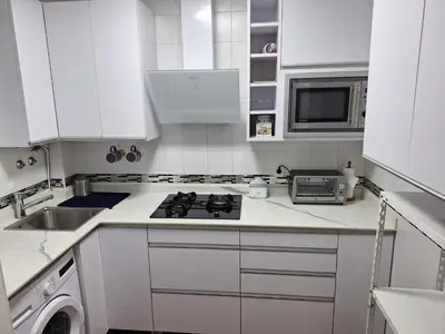 a white kitchen with a stove and a microwave at El Deseo in Novo Sancti Petri
